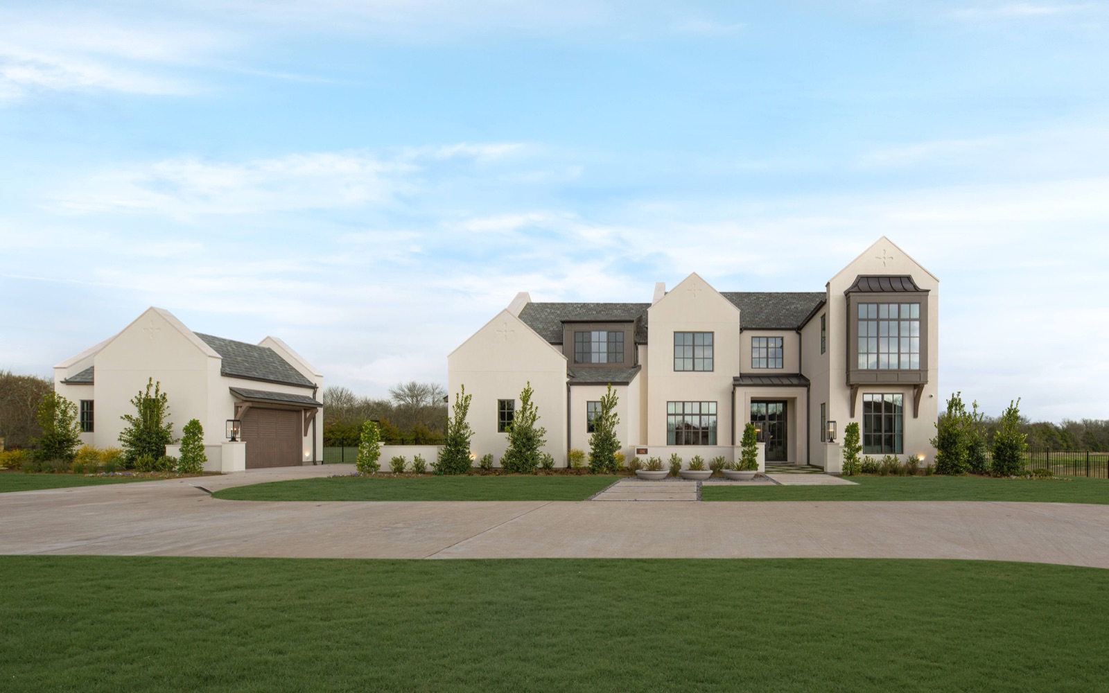Twilight exterior of a large transitional estate with steel windows and a two-story steel window bay.