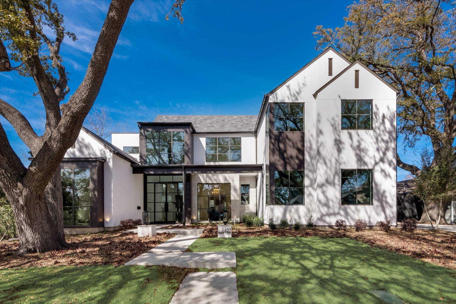 White and gray modern farmhouse with black steel windows and a steel glass entry door.