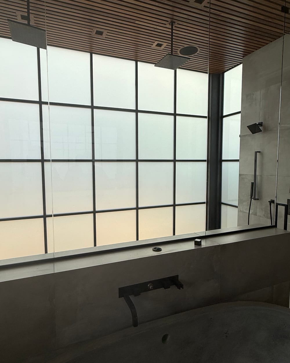 Frosted steel-framed smart glass in a master bathroom, switched for on-demand privacy